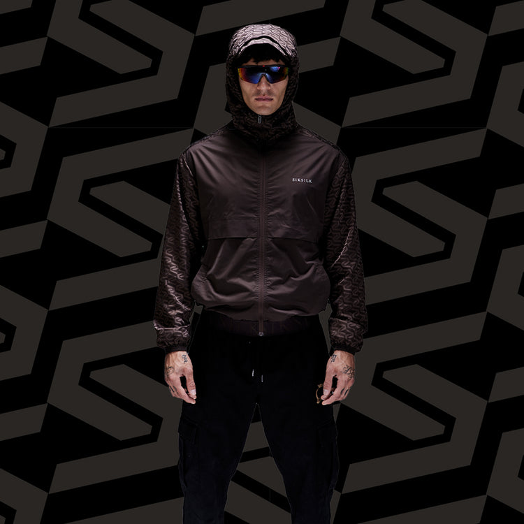 SikSilk Outerwear. Model posing in SikSilk Brown AOP Windbreaker, wearing shades