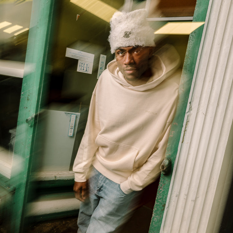 SikSilk Hoodies. Model posing in a shop doorway, wearing SikSilk Ecru Filigree Hoodie