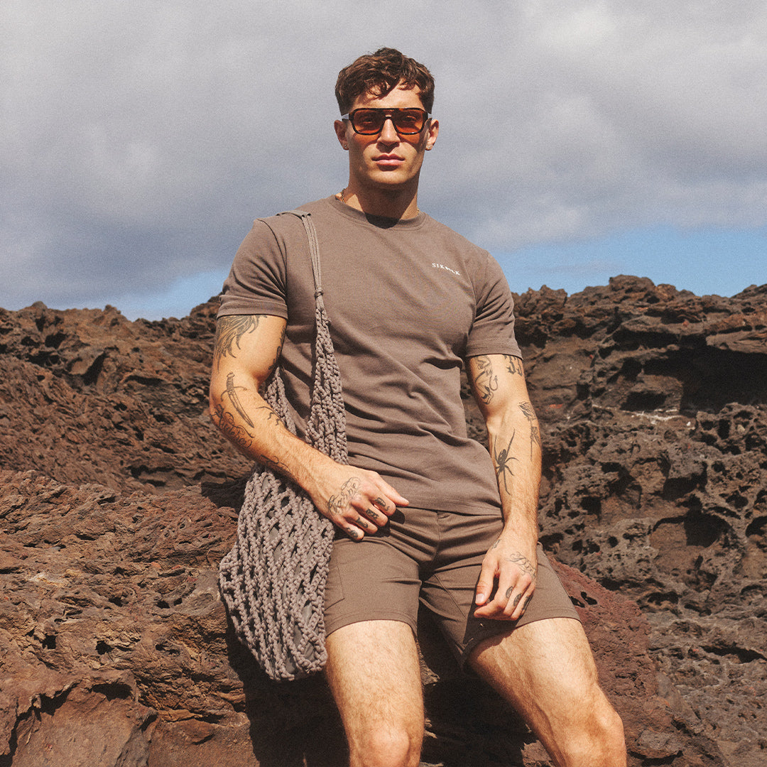 SikSilk model sat on the rocks, in the sun, modelling new T-shirt & Shorts