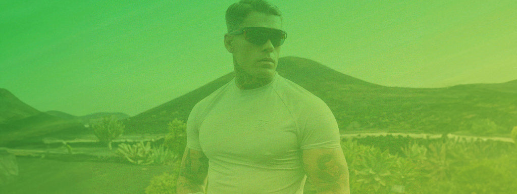 ST. PATRICKS DAY Sale, 20% Off Full Price Styles, 7 - 11pm. Image with a green flash over it. SikSilk model posing in Muscle Fit T-Shirt & shades outdoors in Lanzarote.