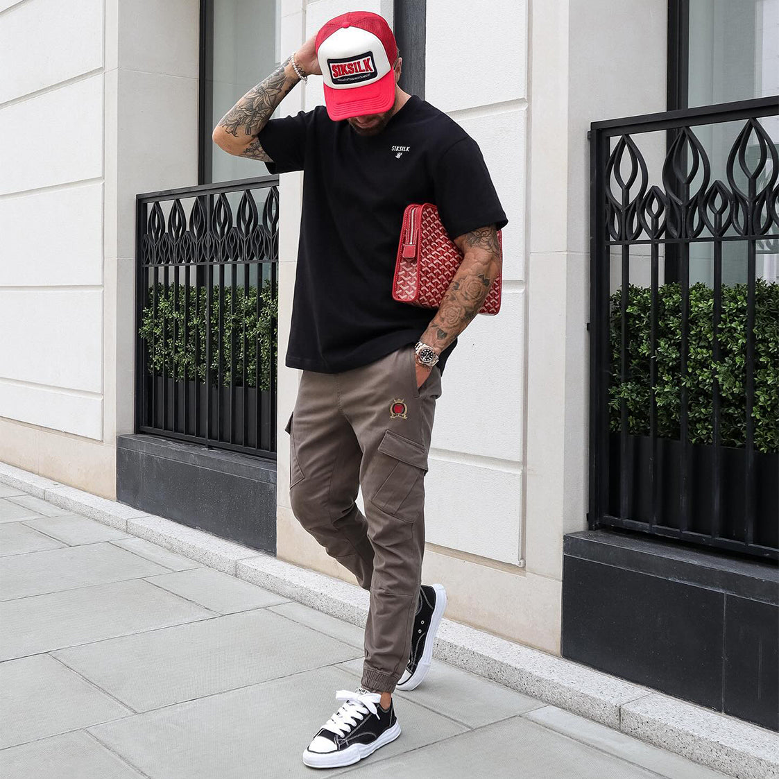 Model posing in Black SikSilk T-Shirt, Brown SikSilk Cargo Trousers & a Red SilkSilk Trucker Cap